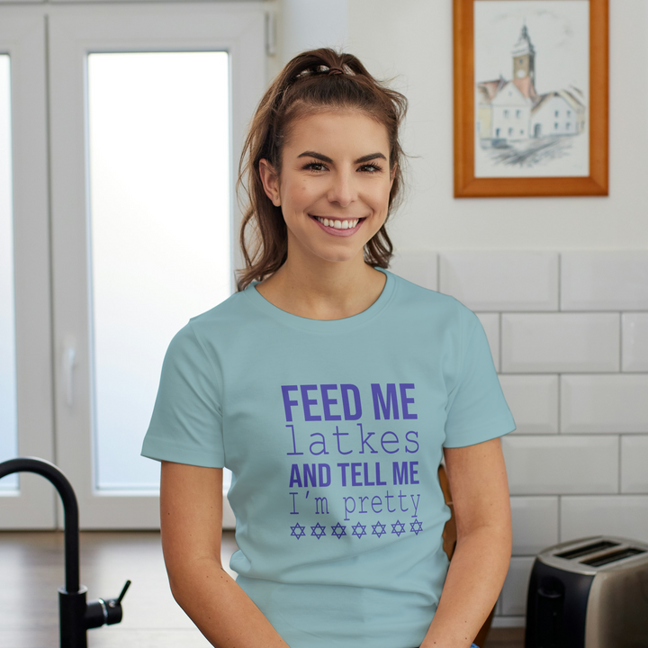 Woman wearing a light blue t-shirt with text in a kitchen