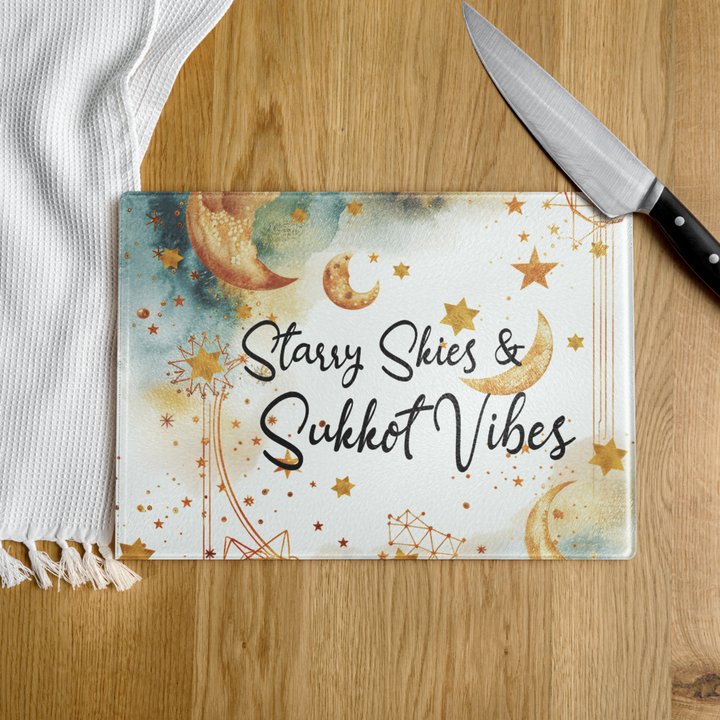 Cutting board with 'Starry Skies & Sukkot Vibes' design on a wooden surface with a knife.