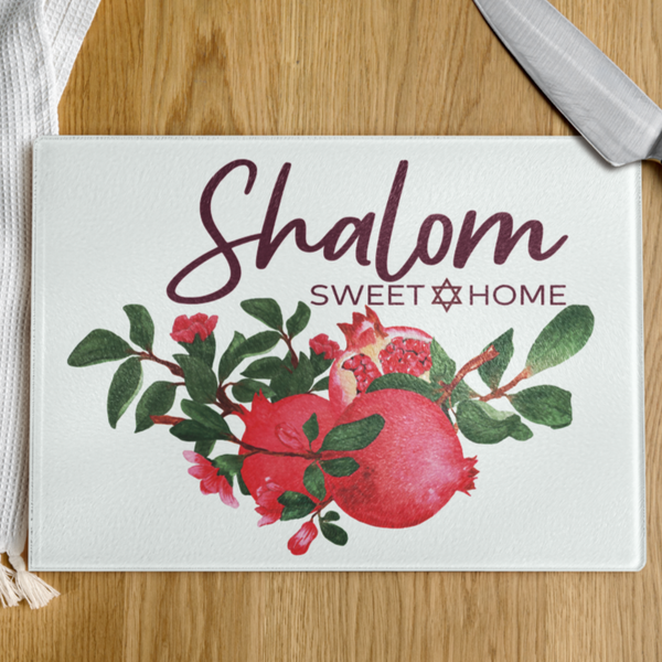 Chopping board with 'Shalom Sweet Home' text and pomegranate design on a wooden surface.