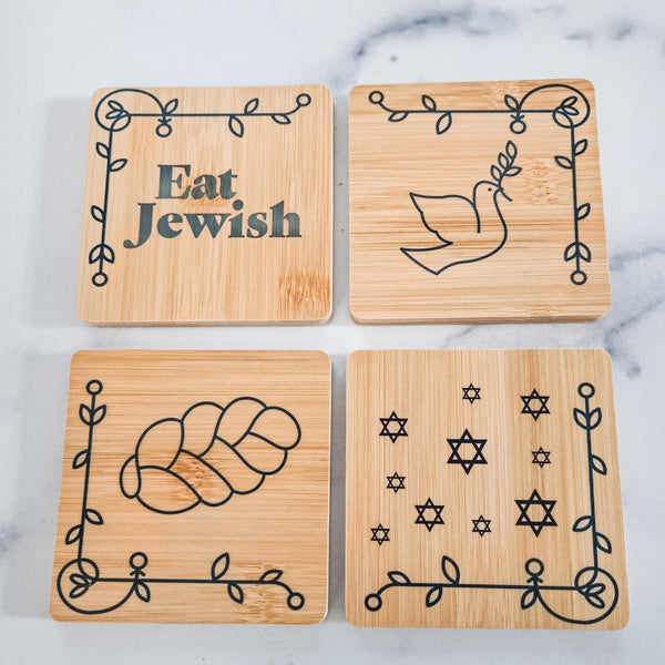 Set of four square bamboo coasters with challah, dove, Star of David, and Eat Jewish artwork, in a holder labeled “Eat Jewish.”