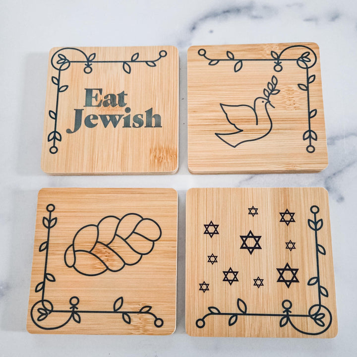 Set of four square bamboo coasters with challah, dove, Star of David, and Eat Jewish artwork, in a holder labeled “Eat Jewish.”